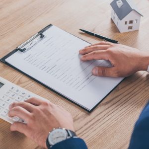 cropped view of businessman reading property management agreement and using calculator